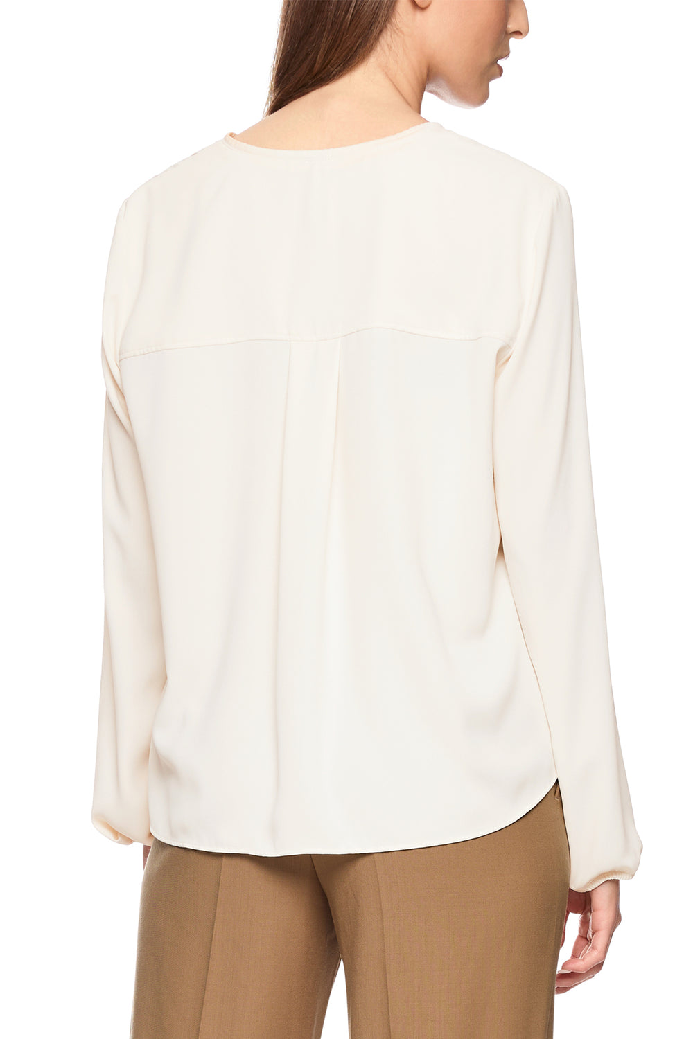Woman wearing a white blouse and beige pants on a white background