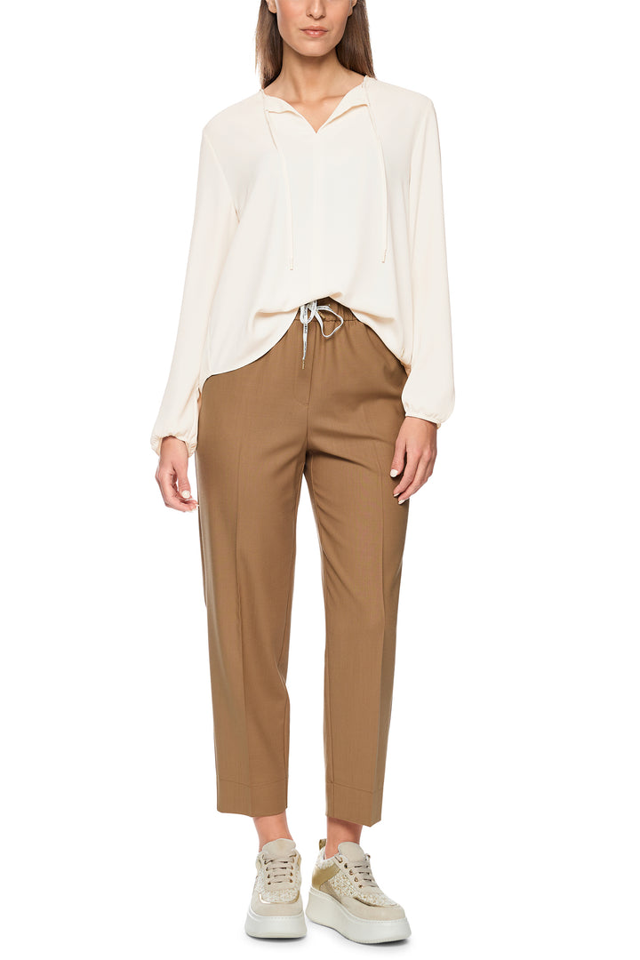 Woman wearing a white blouse and brown pants on a white background