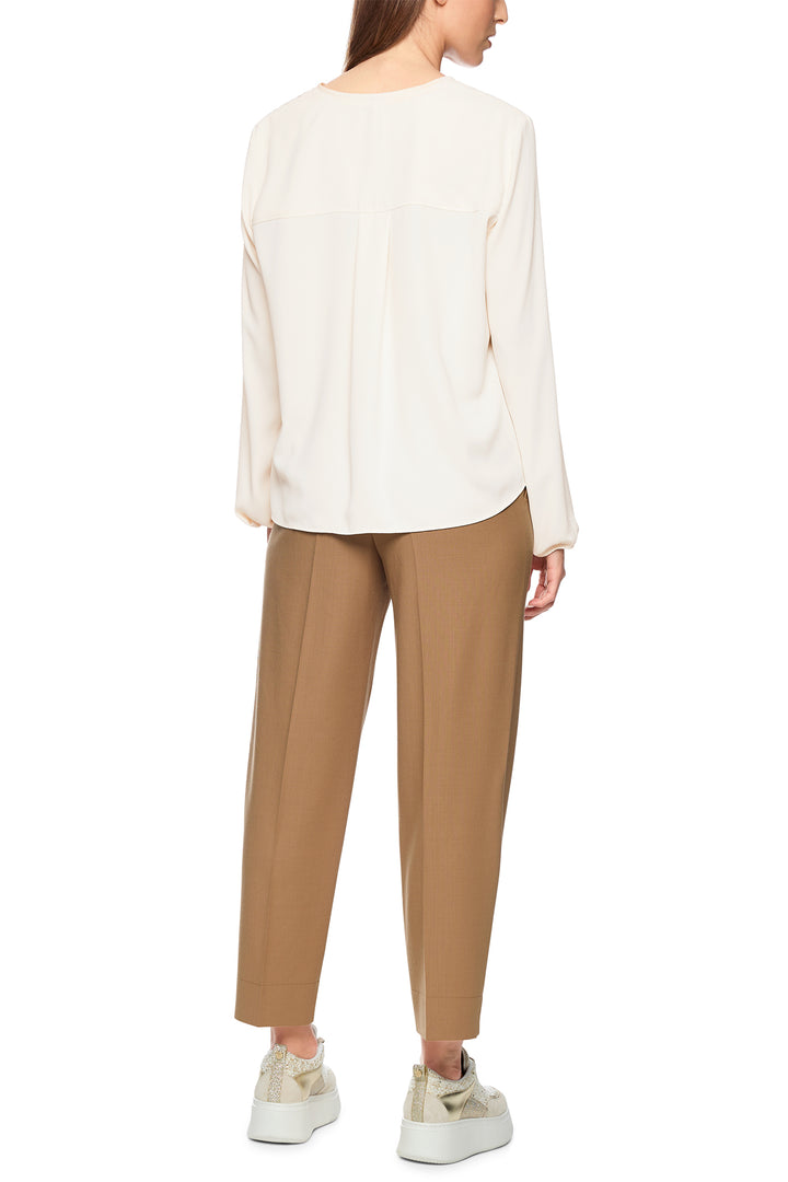 Person wearing a white blouse and beige pants on a white background