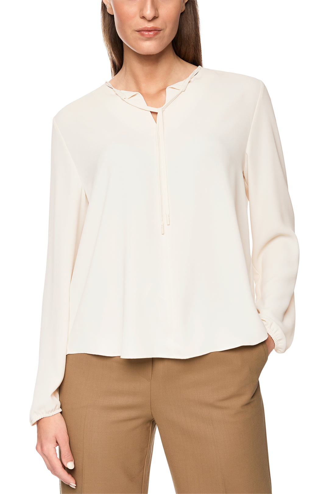 Woman wearing a white blouse and beige pants on a white background