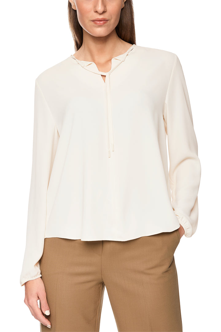 Woman wearing a white blouse and beige pants on a white background