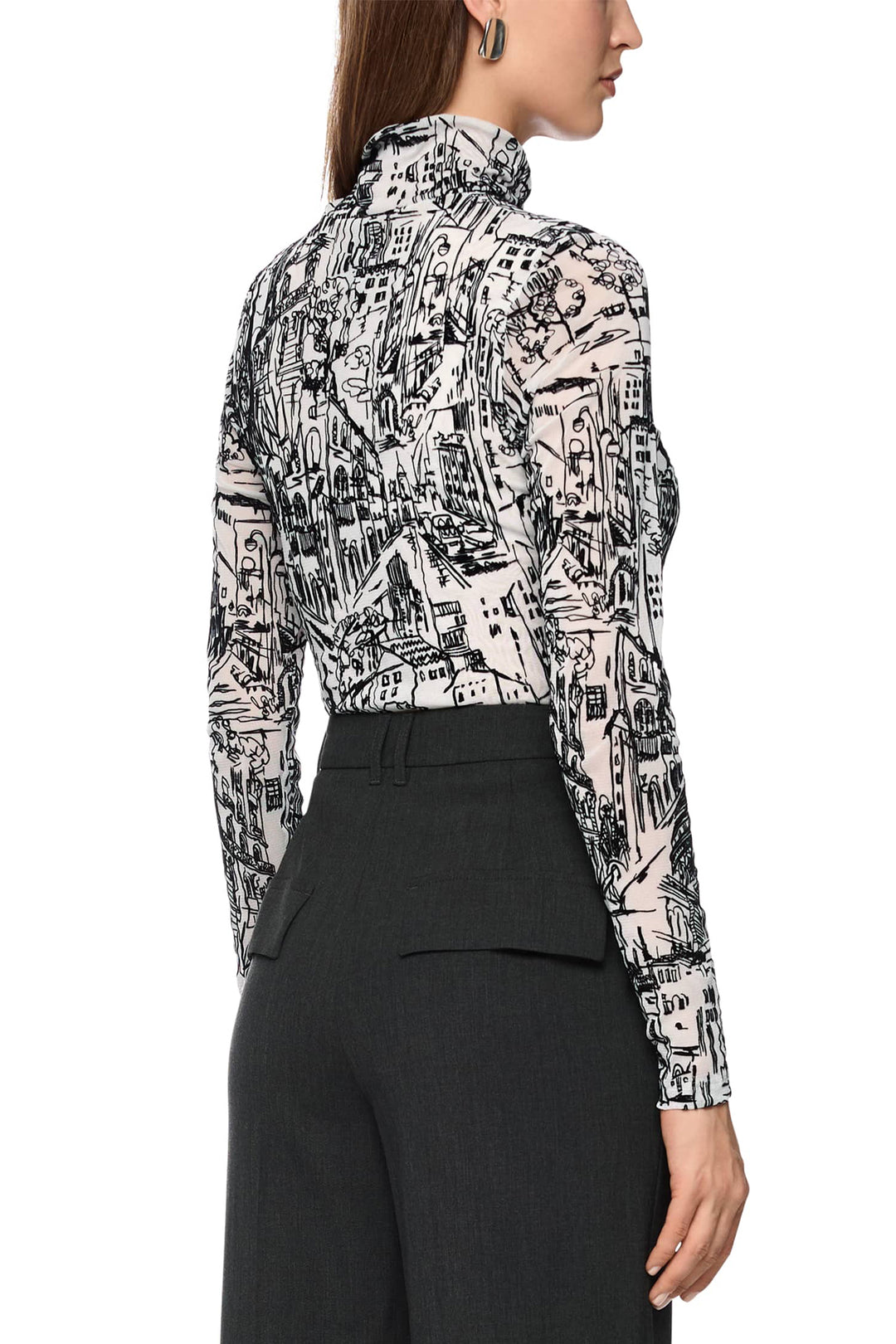 Person wearing a patterned blouse with long sleeves and black pants on a white background