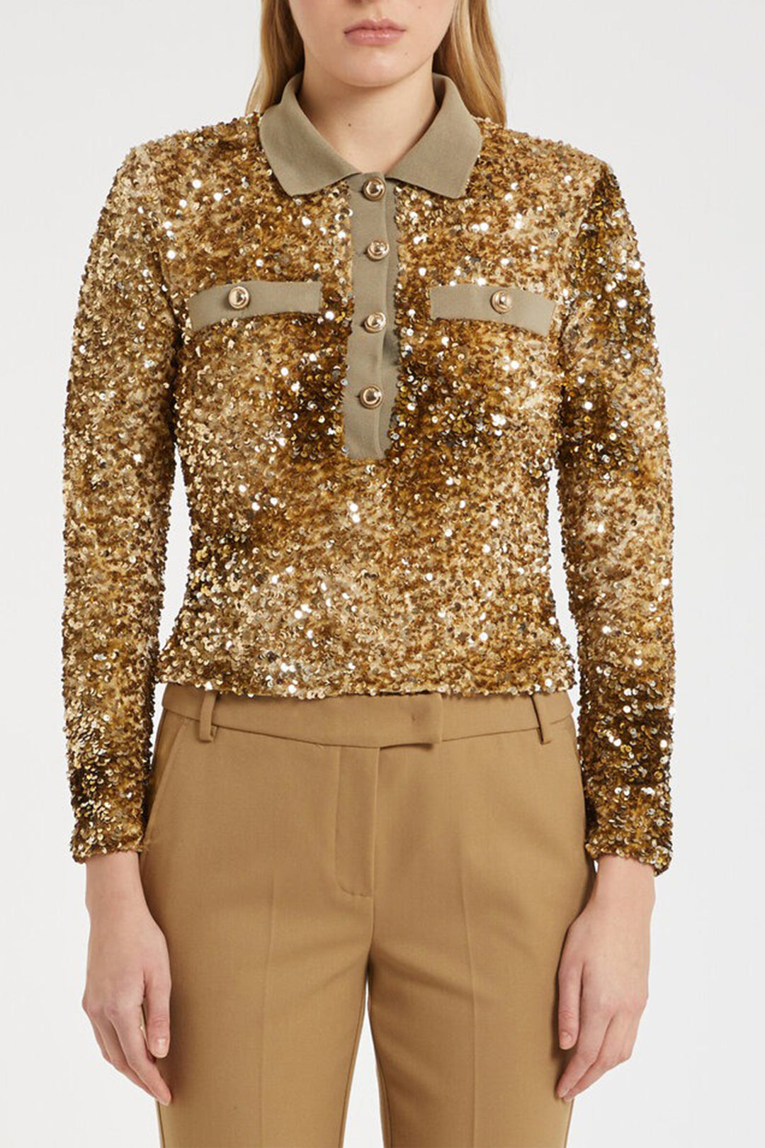 Gold sequin blouse with beige collar and buttons worn by a person on a white background