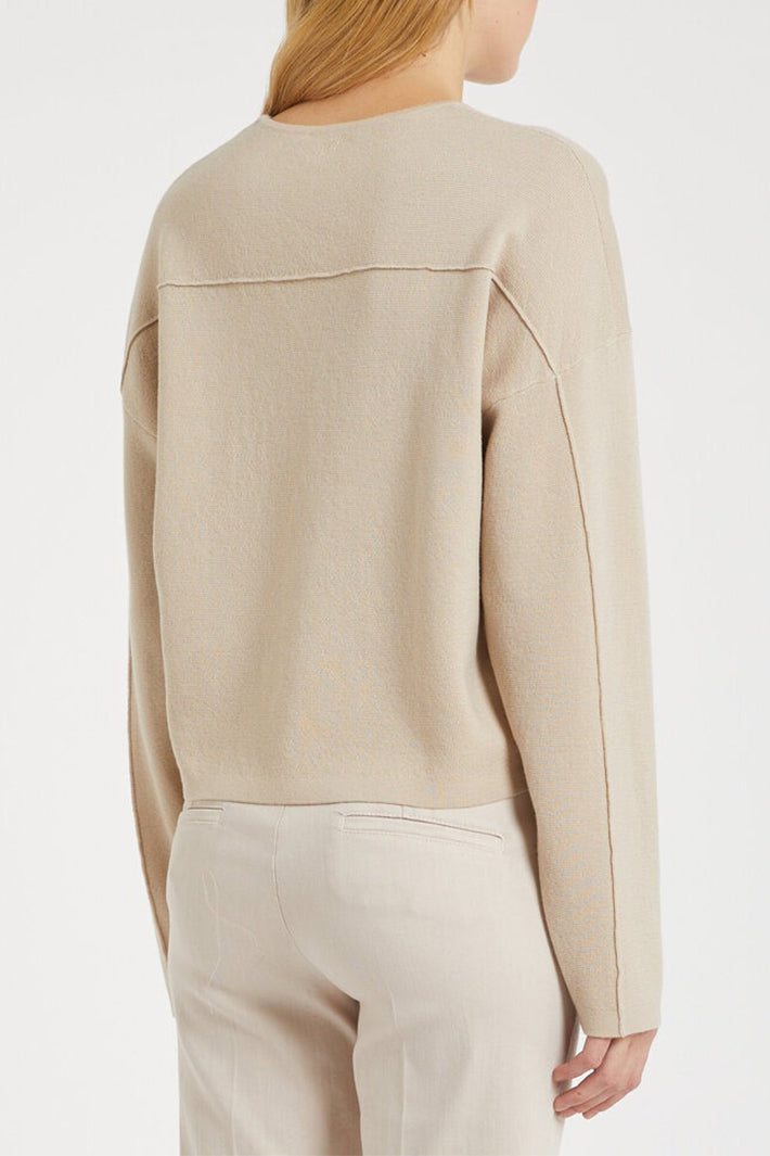 Beige sweater worn by a person on a white background