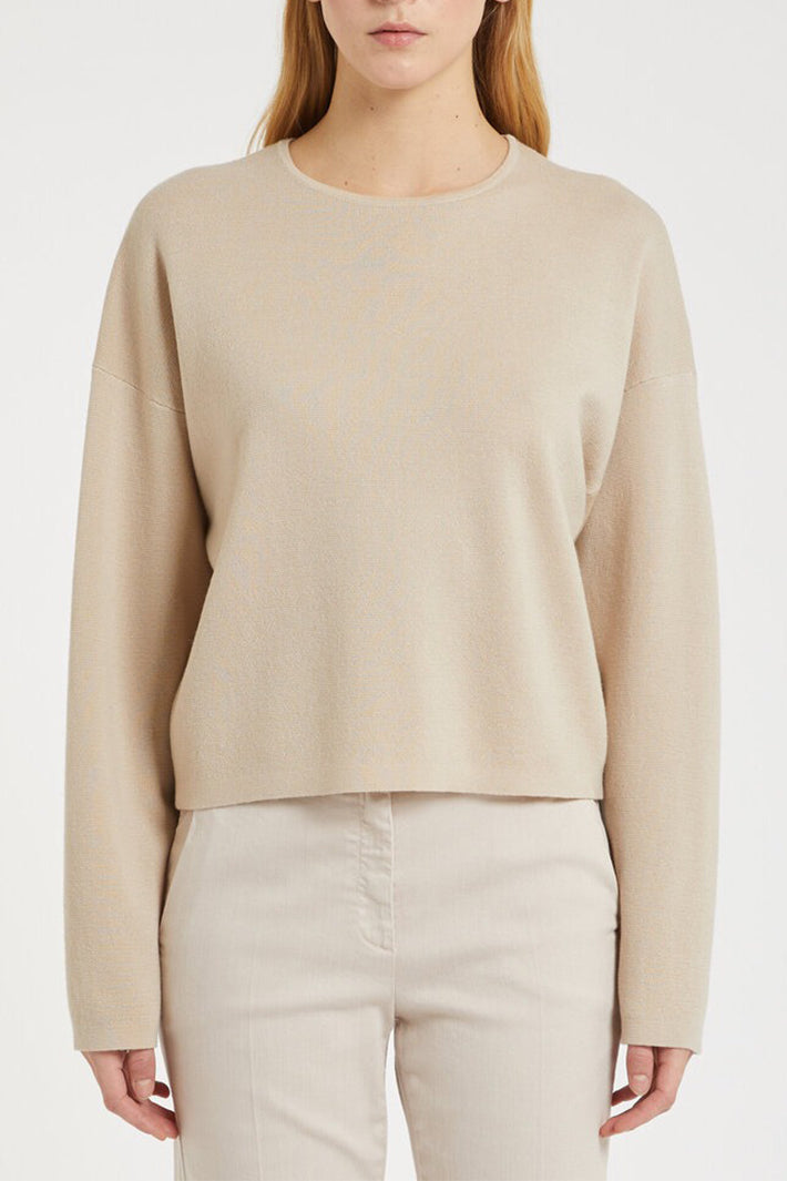 Person wearing a beige sweater and pants on a white background