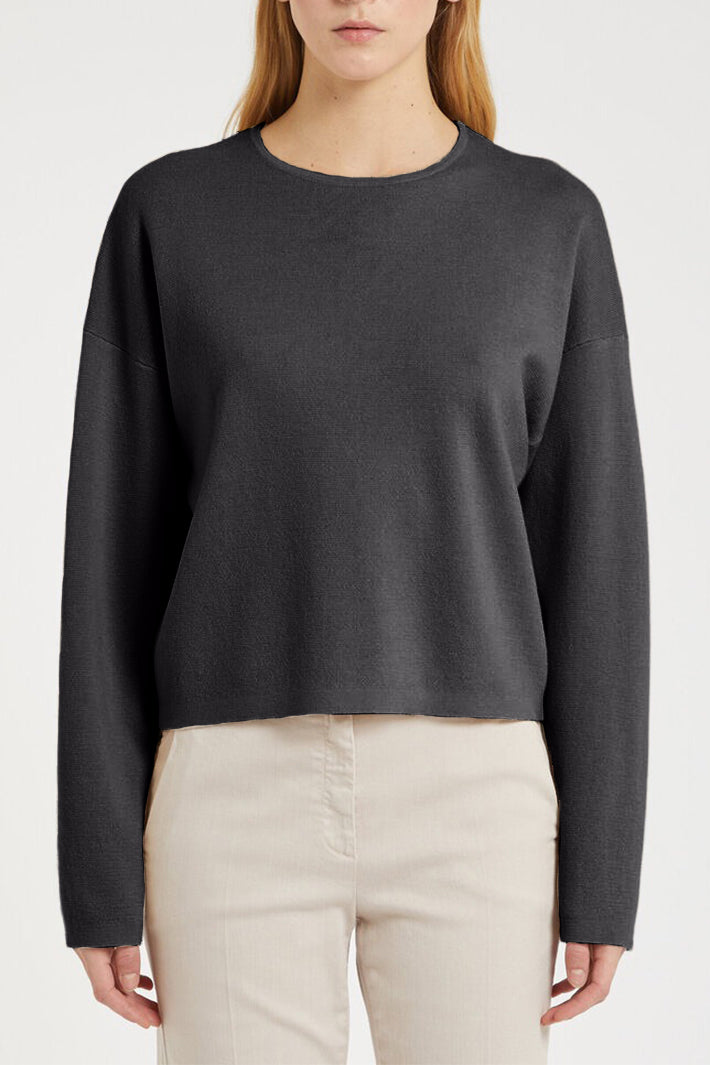 Person wearing a dark gray sweater and beige pants on a light gray background