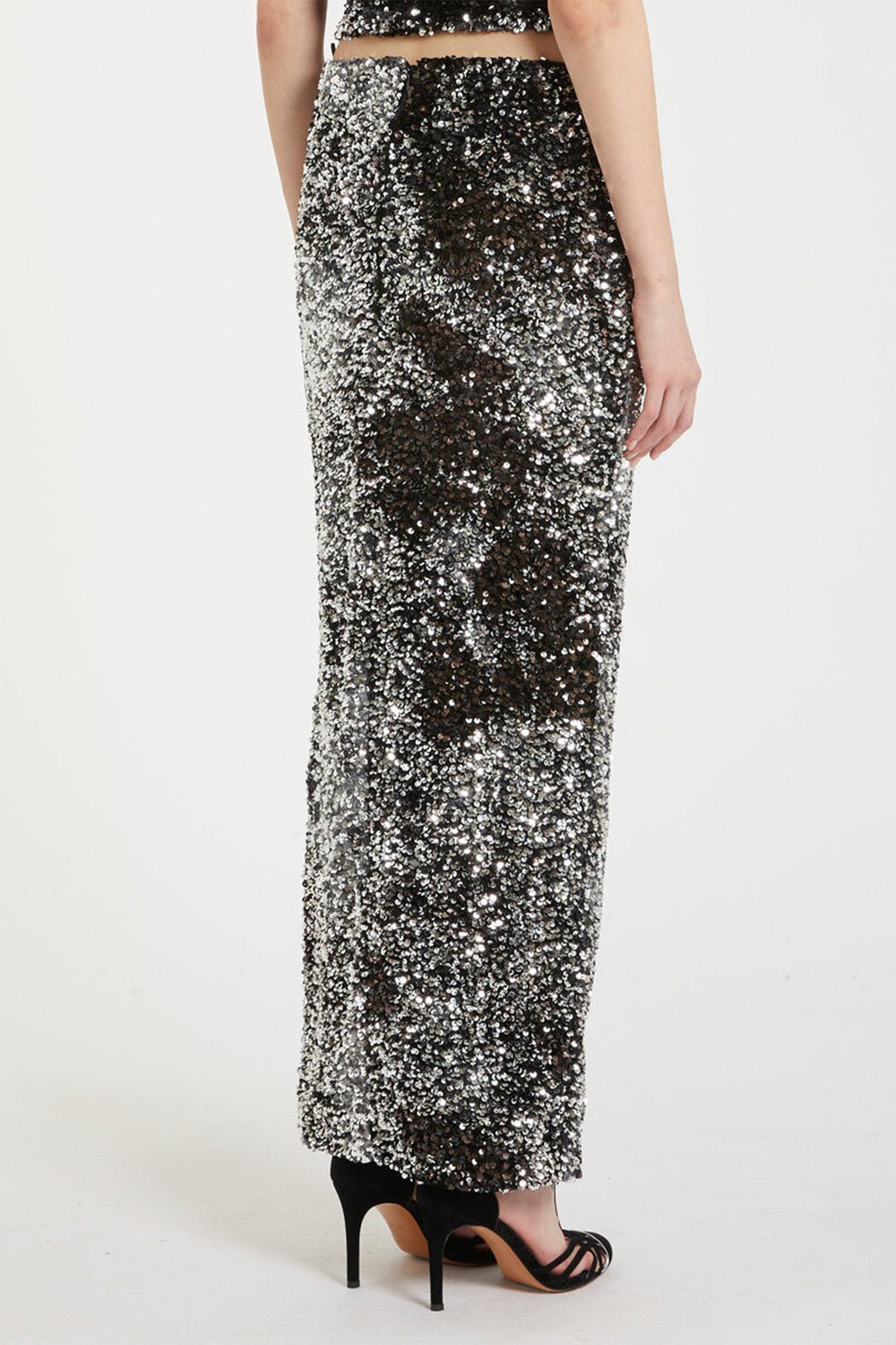Person wearing a long, sequined skirt on a white background