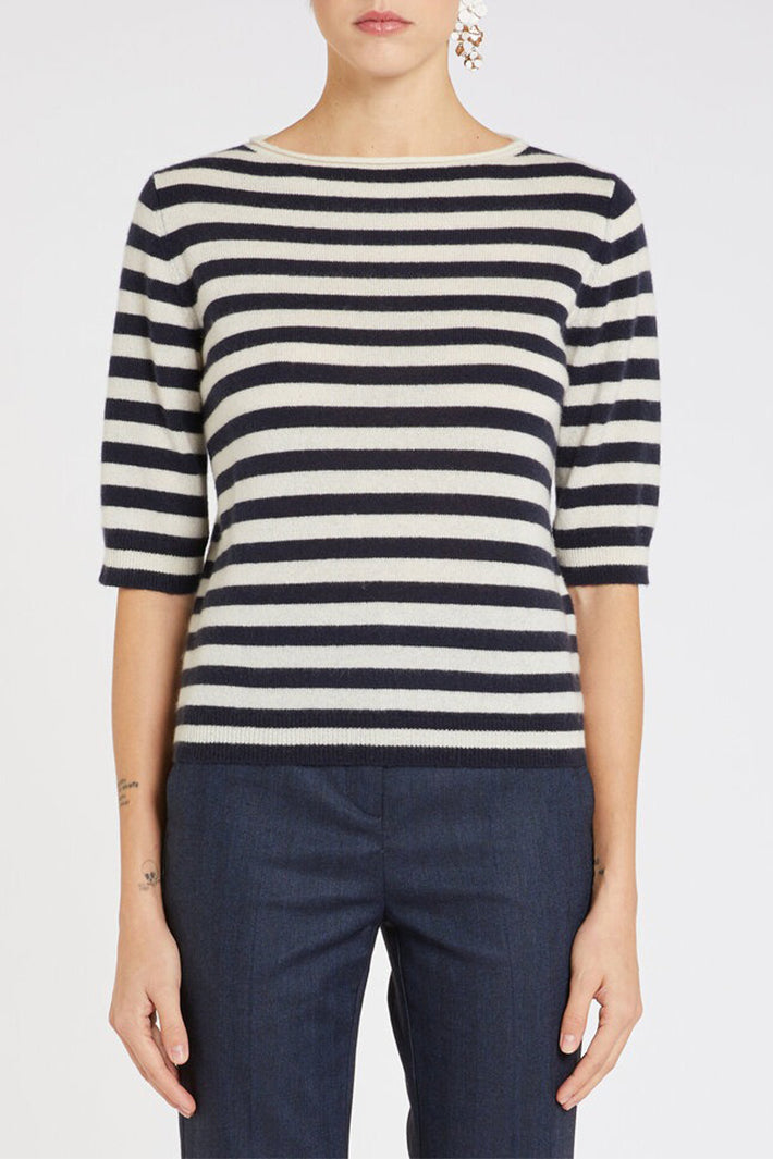 Person wearing a navy and white striped sweater with navy pants on a plain background