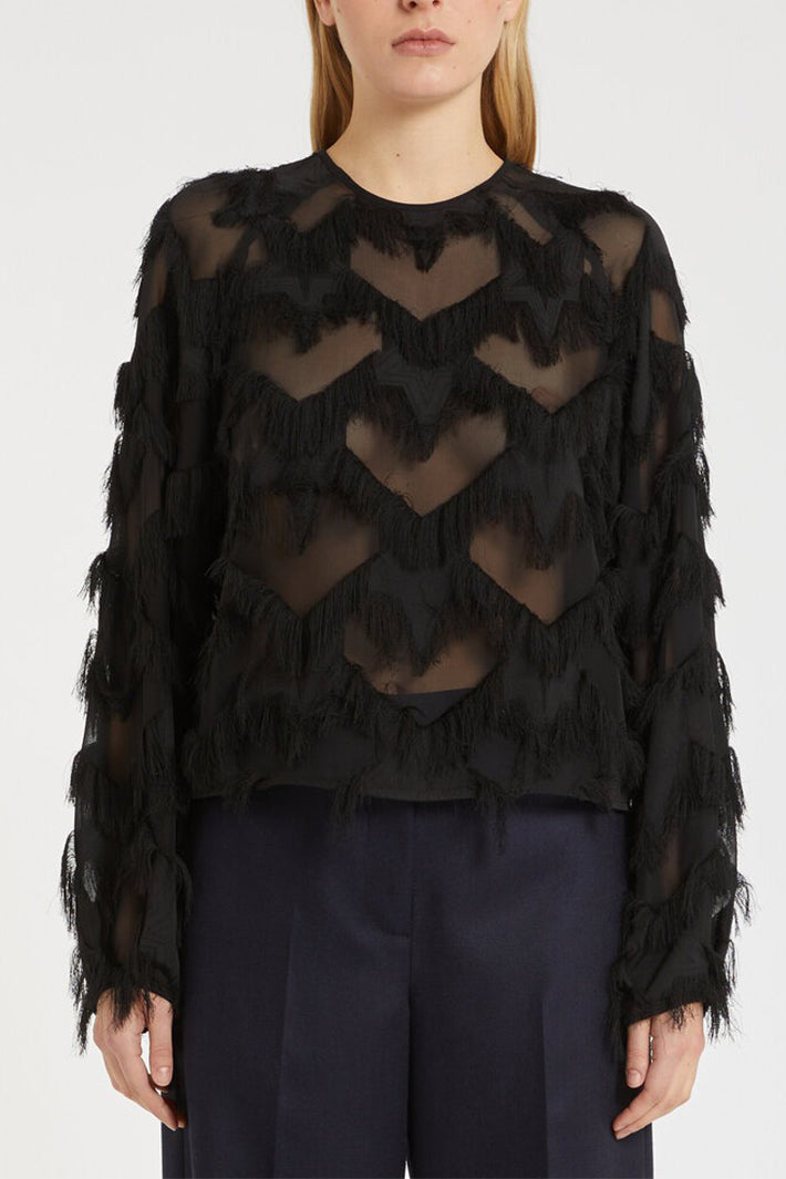 Black sheer sweater with fringe details worn by a model on a white background