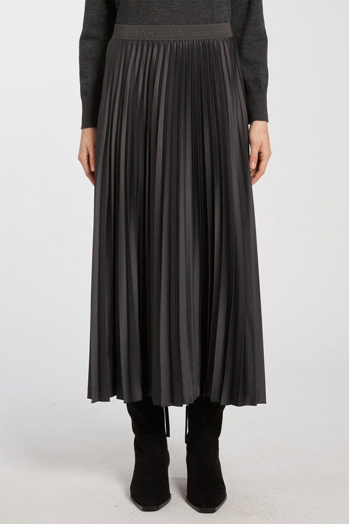 Person wearing a black pleated skirt with a plain background