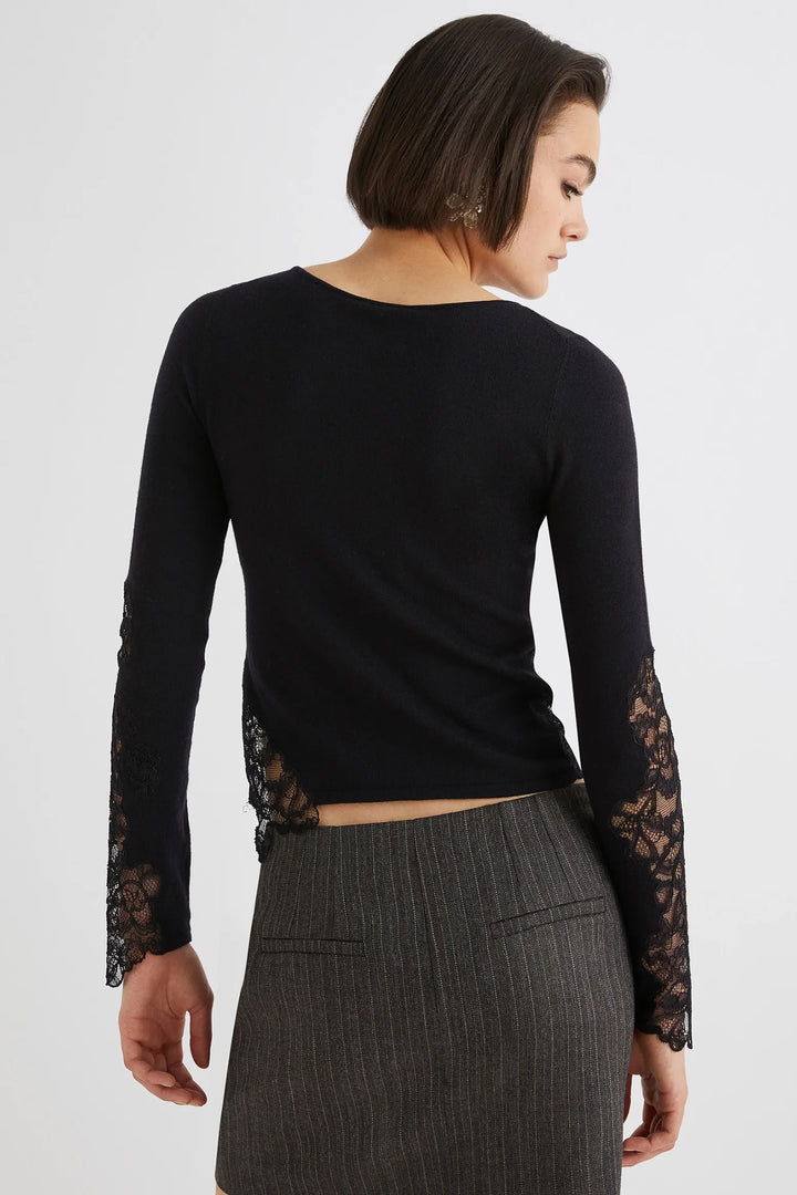 Woman wearing a black long-sleeve top with lace sleeves on a white background