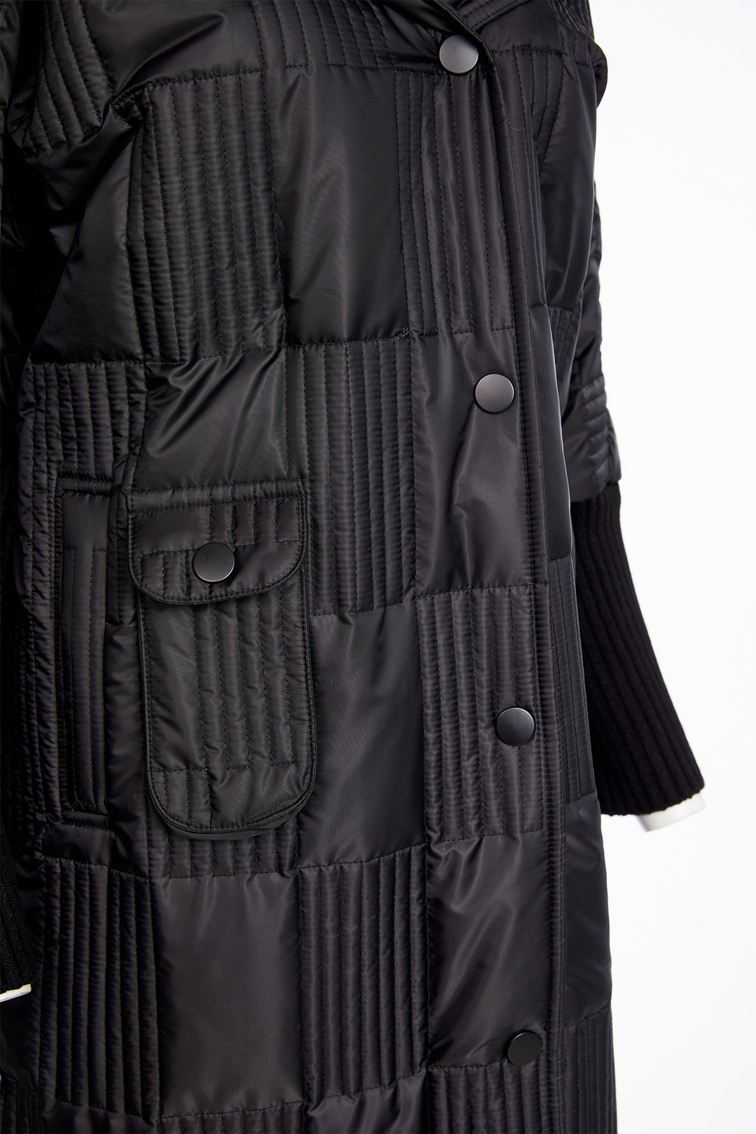 Close-up of a black quilted coat with buttons on a white background