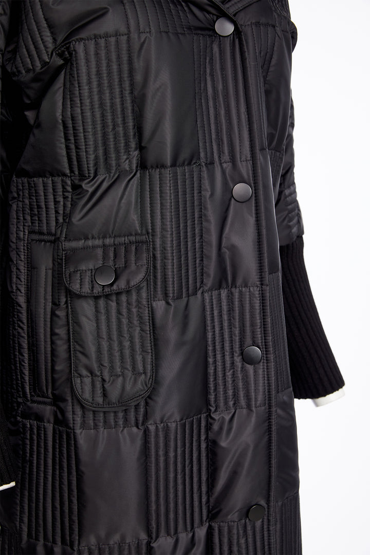 Close-up of a black quilted coat with buttons on a white background