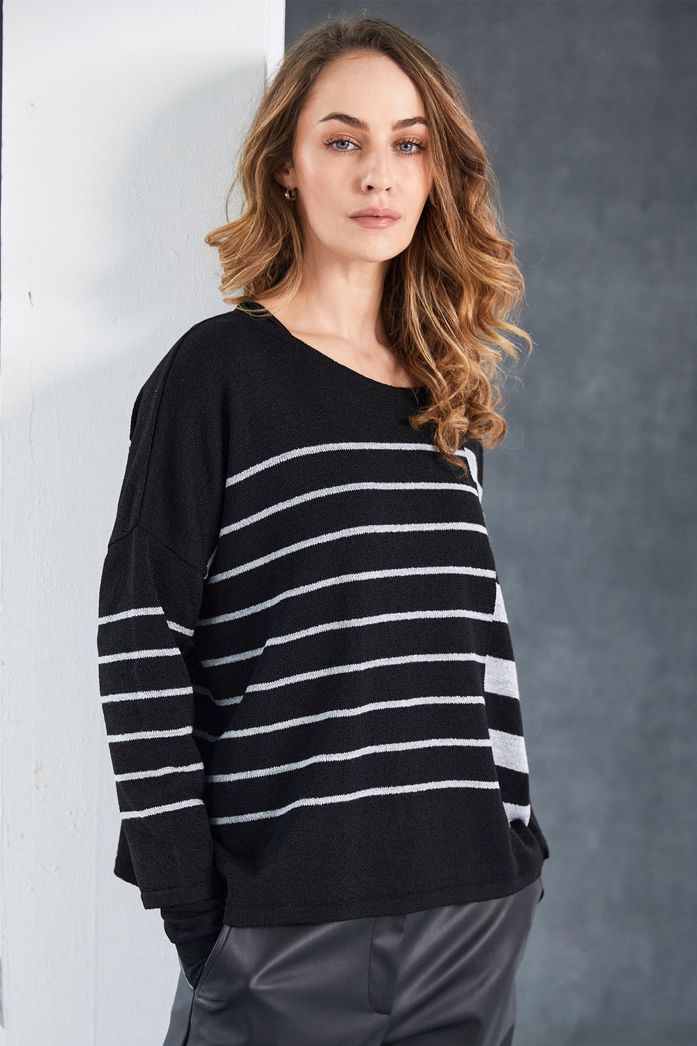 Woman wearing a black and white striped sweater against a gray background