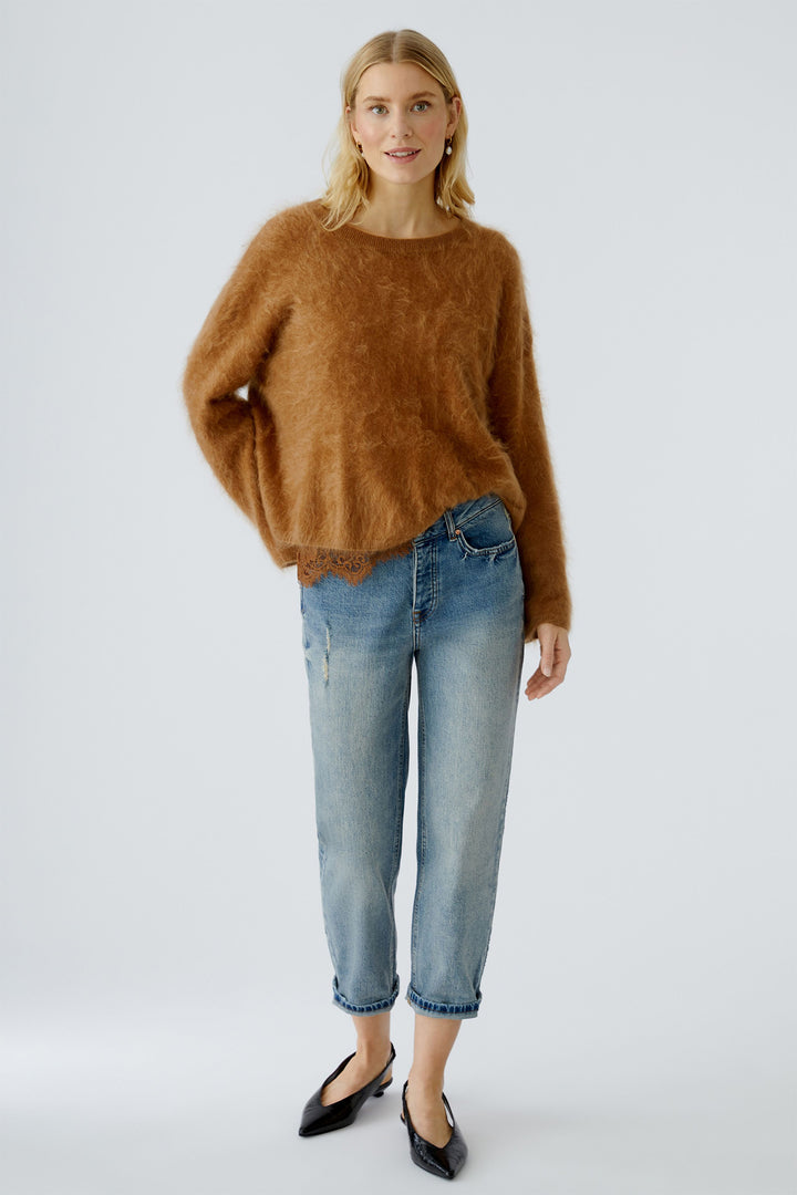 Woman wearing a brown sweater and blue jeans on a white background