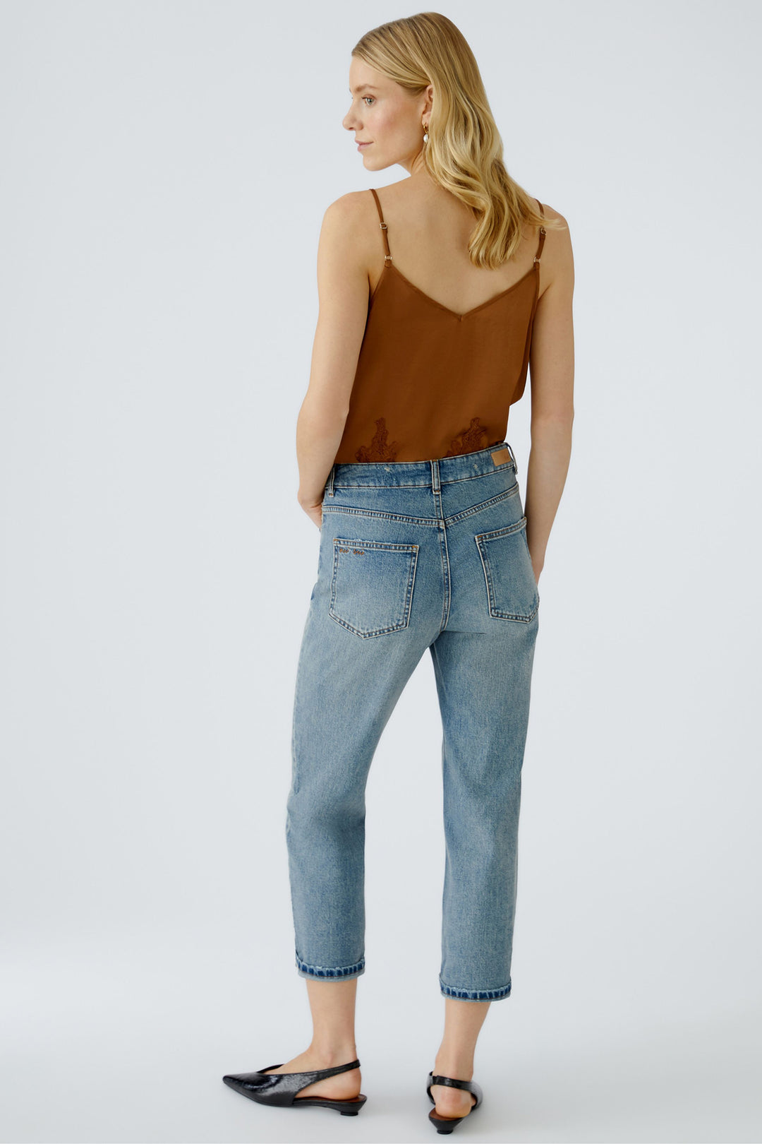 Woman wearing a brown top and blue jeans on a white background