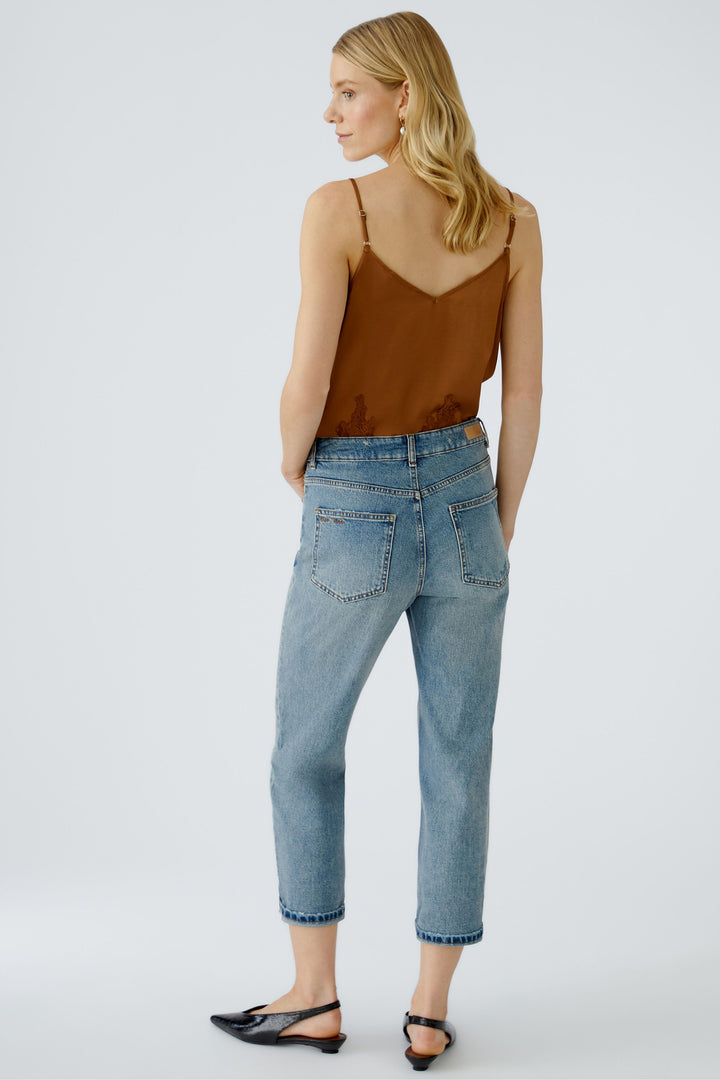 Woman wearing a brown top and blue jeans on a white background