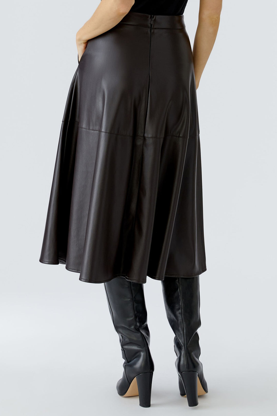 Brown faux leather skirt and boots worn by a person on a white background