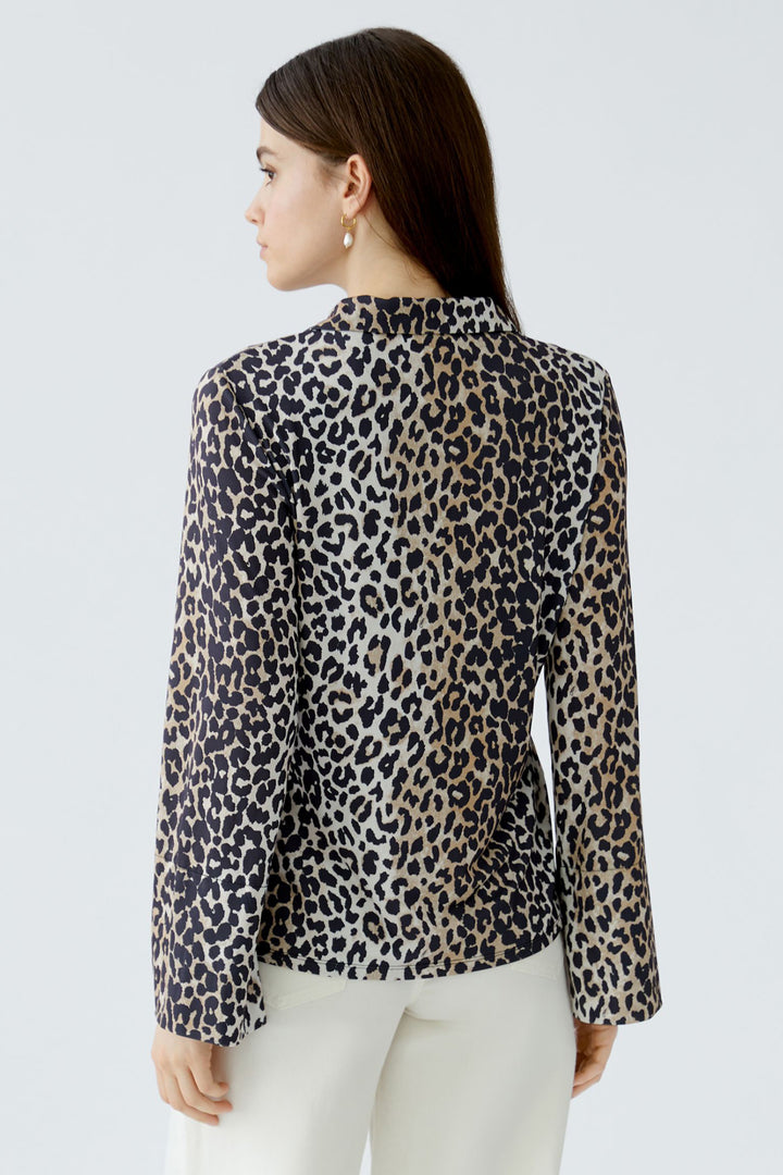 Woman wearing a leopard print blouse against a light gray background