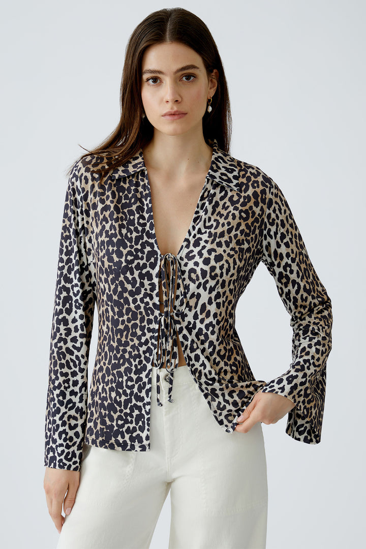 Woman wearing a leopard print blouse with long sleeves on a white background