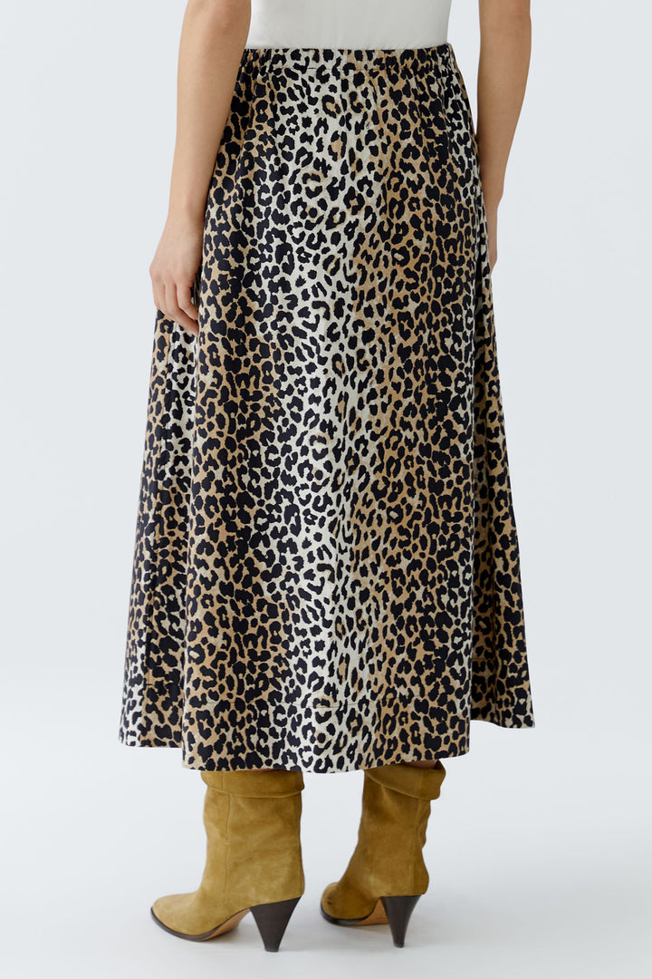Person wearing a leopard print skirt with mustard yellow boots on a white background