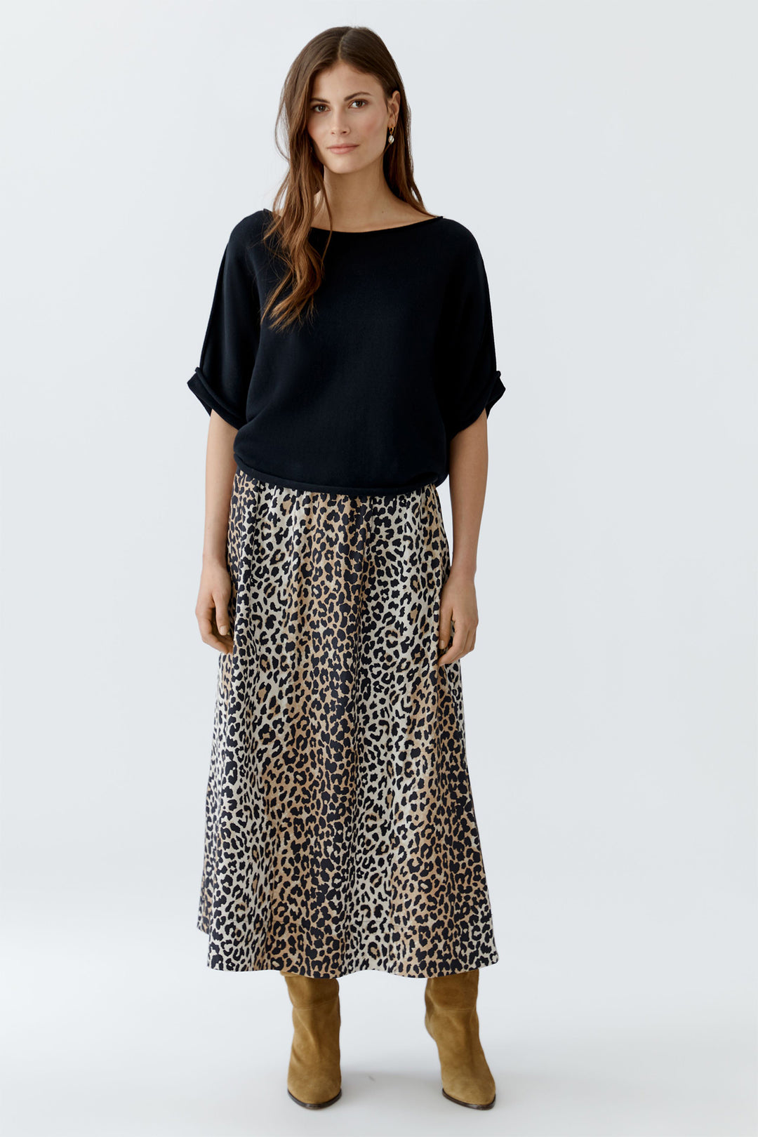 Woman wearing a black top and leopard print skirt on a white background