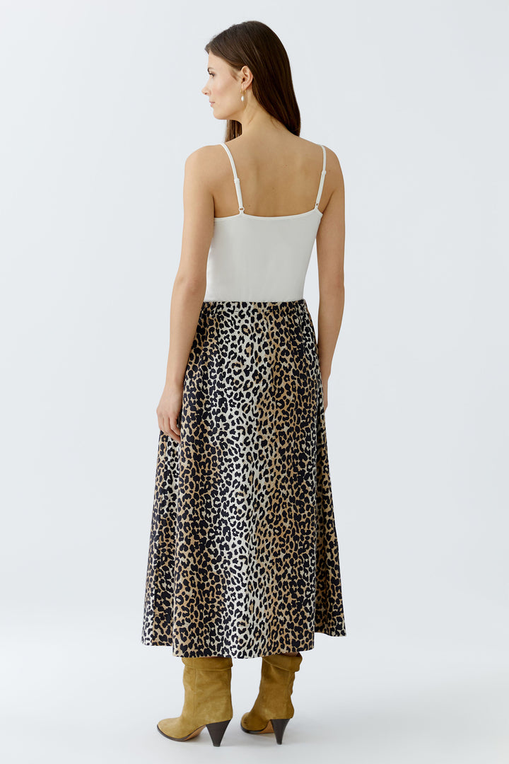 Woman wearing a white top and leopard print skirt on a white background