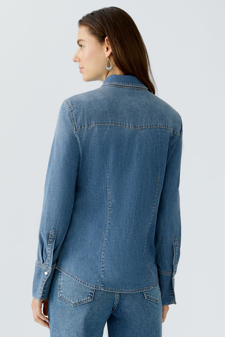 Woman wearing a blue denim jacket on a light gray background