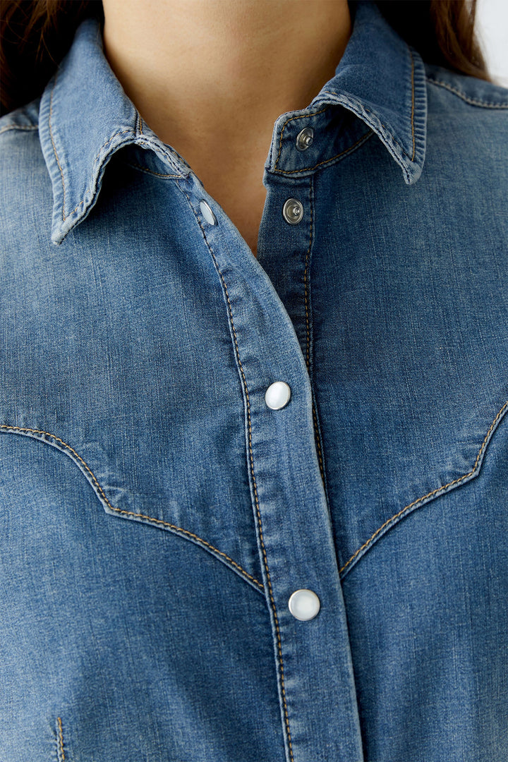 Close-up of a blue denim shirt with a collar and buttons.