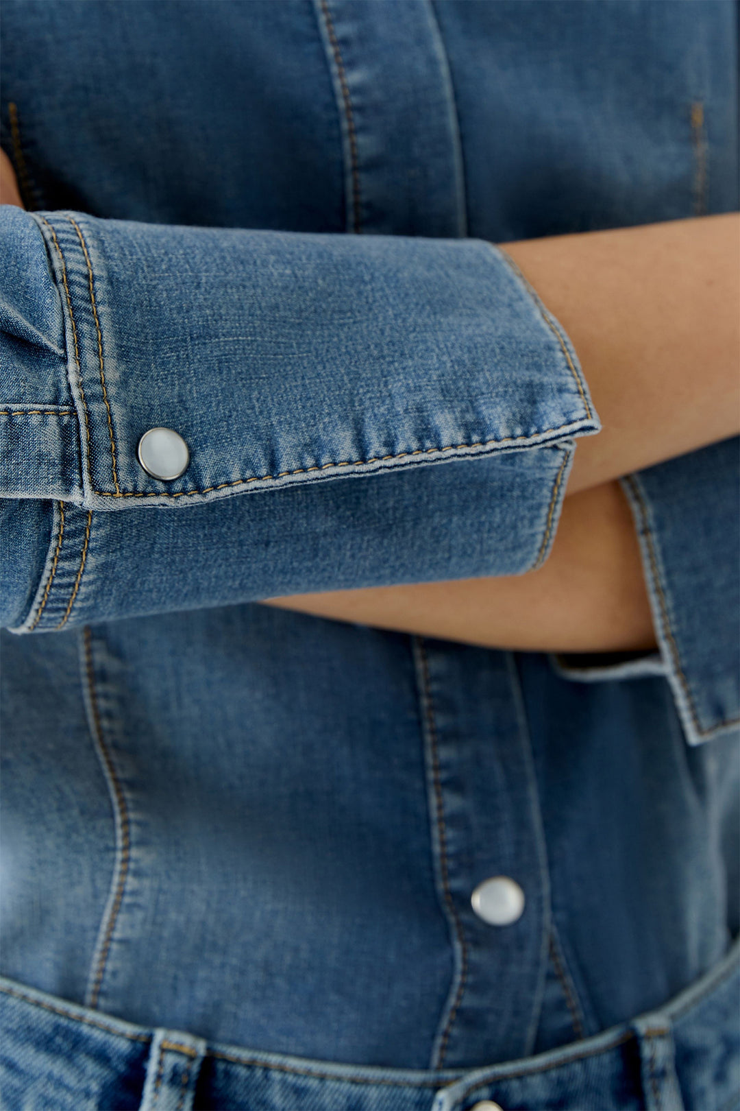 Close-up of a person wearing a blue denim jacket with rolled-up sleeves.