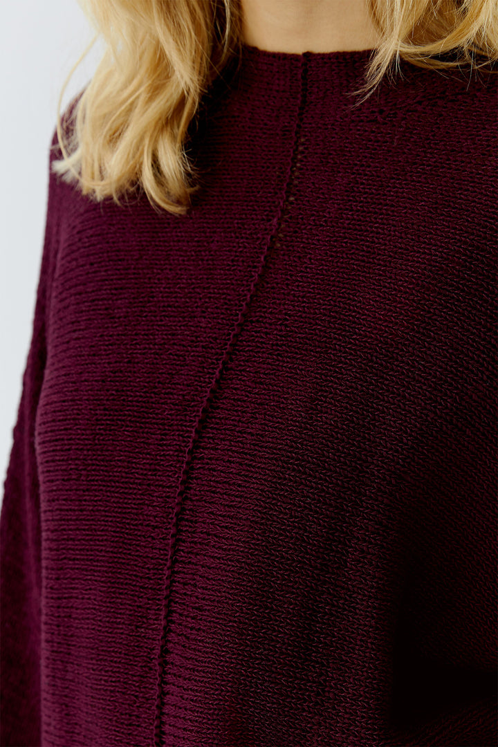 Close-up of a maroon sweater with a plain background