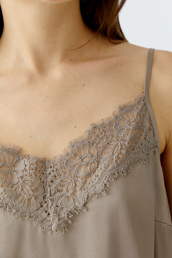 Close-up of a beige lace-trimmed top on a neutral background