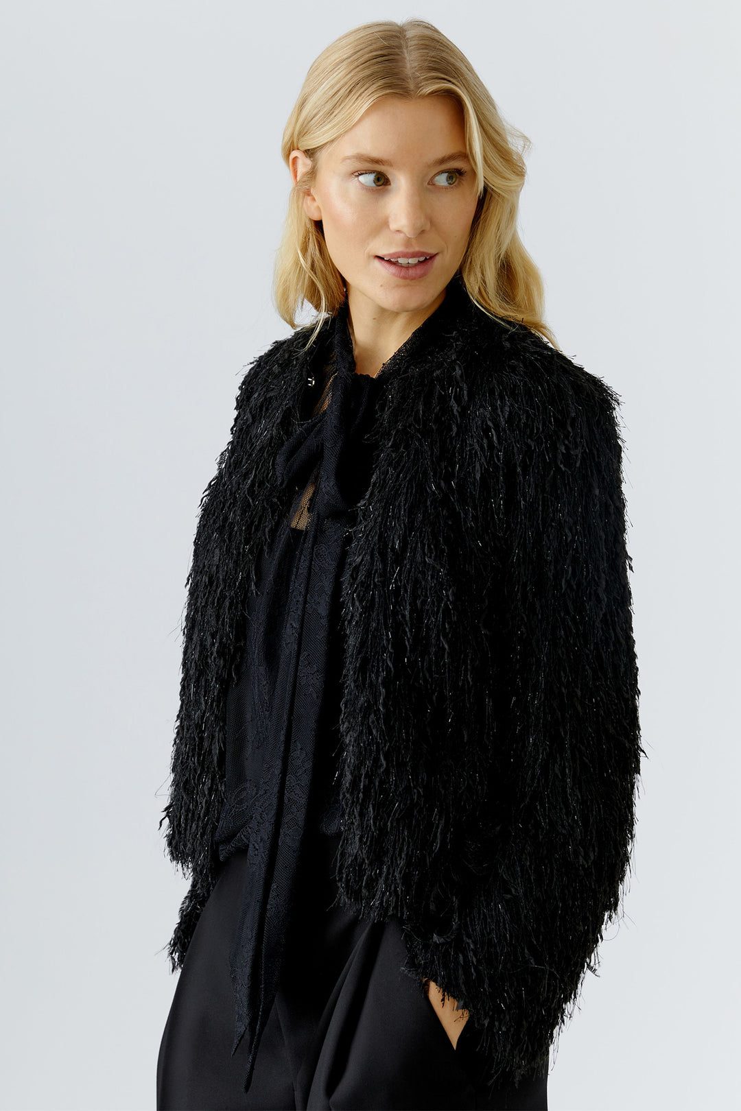 Woman wearing a black fluffy jacket against a light gray background