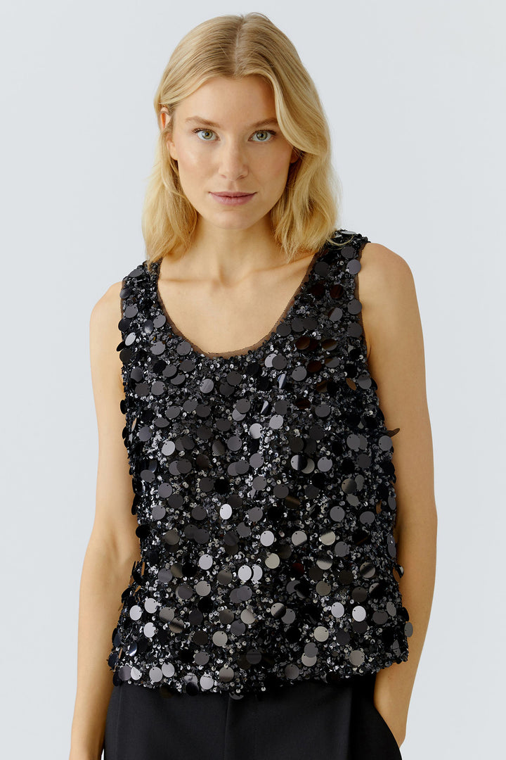 Woman wearing a black sequin top against a light gray background