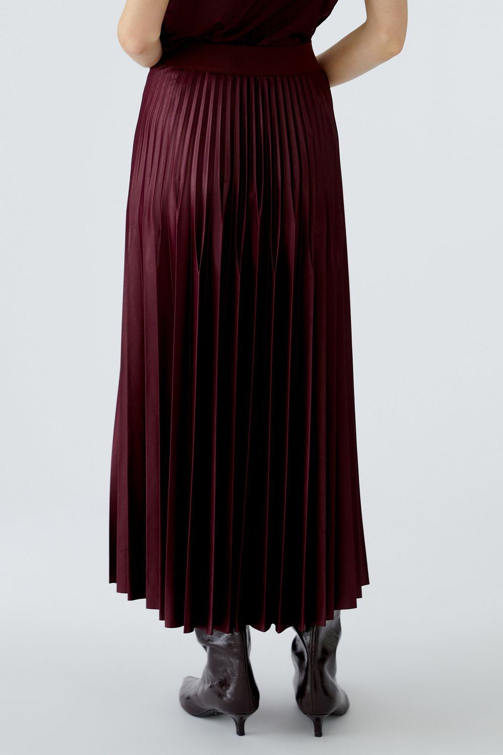 Person wearing a burgundy pleated skirt on a white background