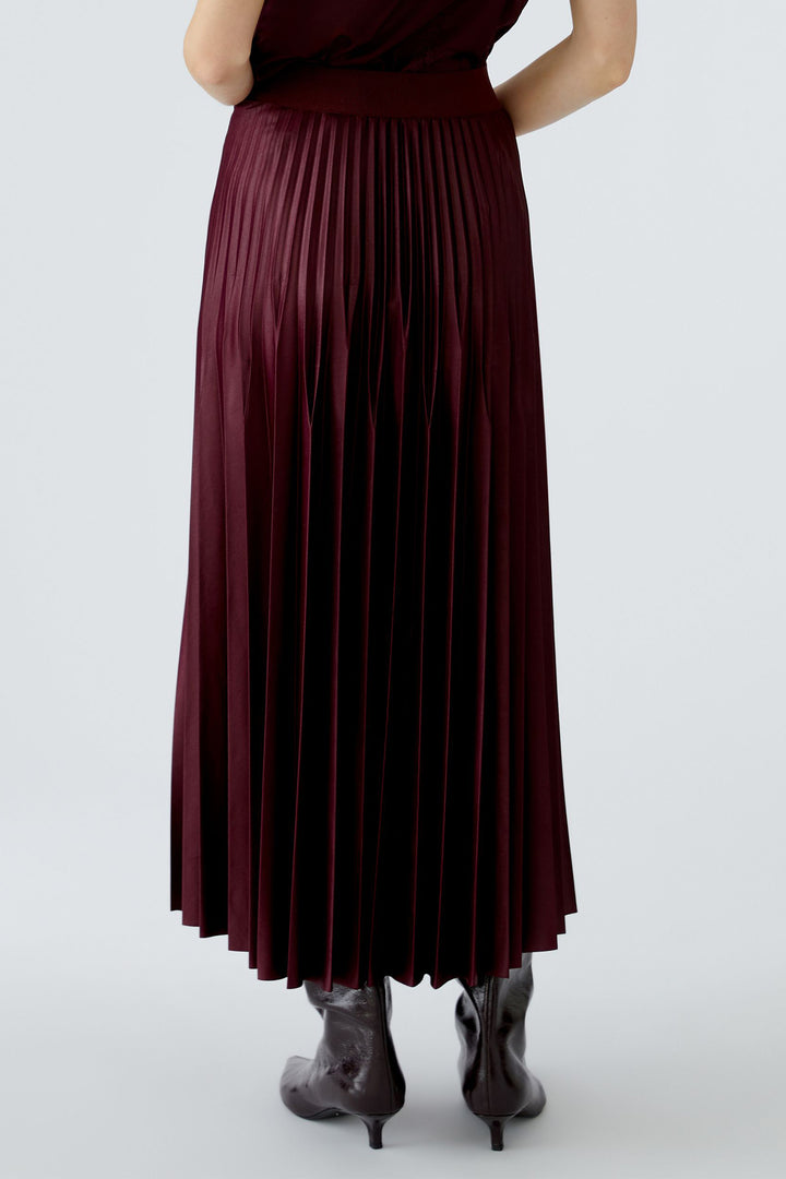 Person wearing a burgundy pleated skirt on a white background