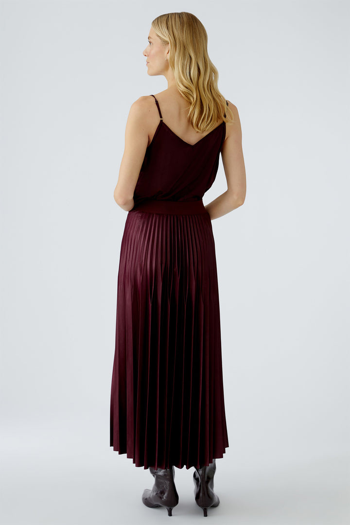 Woman wearing a burgundy pleated dress on a white background