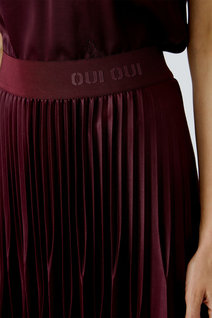 Maroon pleated skirt with waistband displaying 'OUI' on a plain background