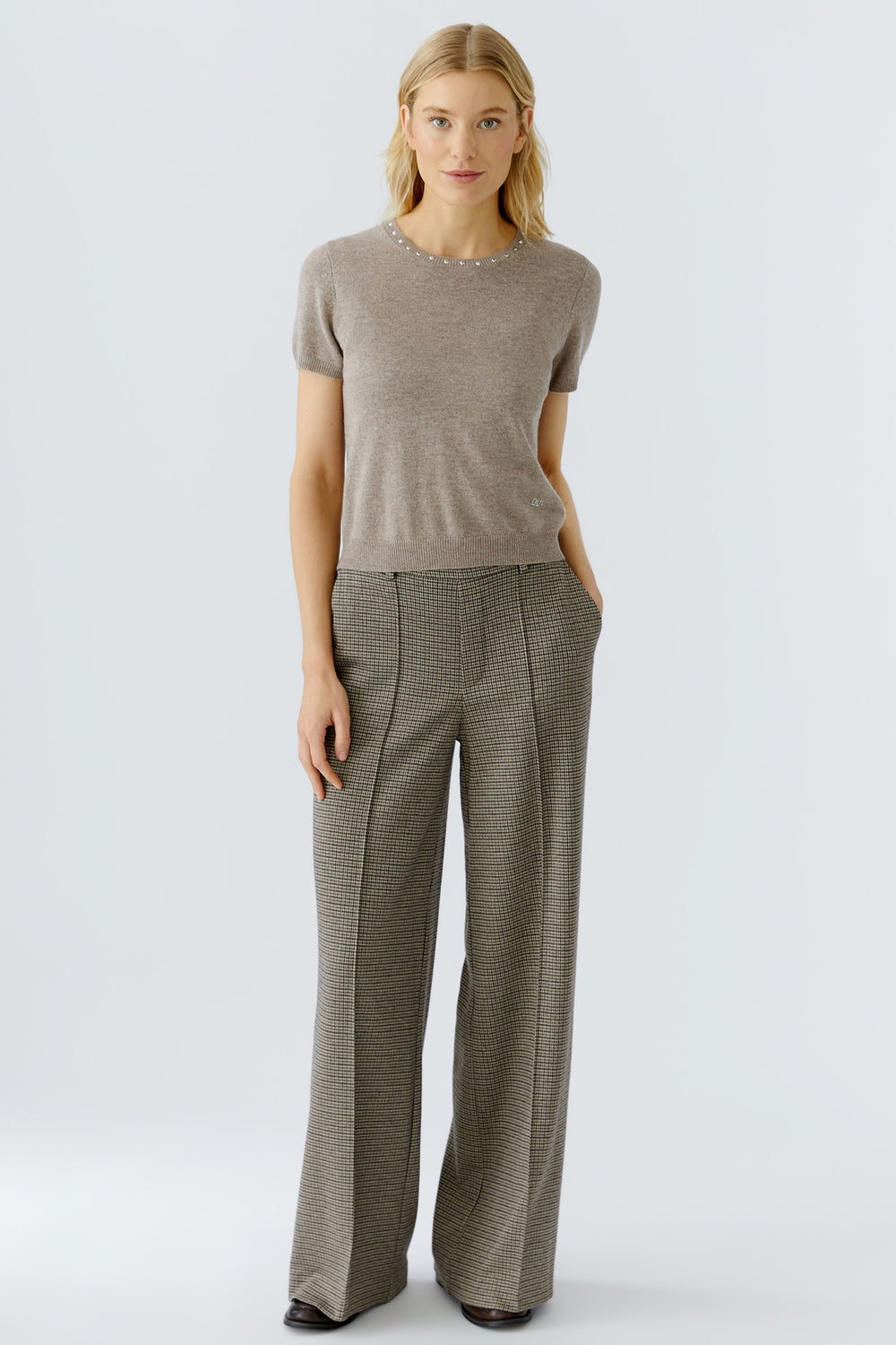 Woman wearing a brown short-sleeve top and wide-leg pants on a white background