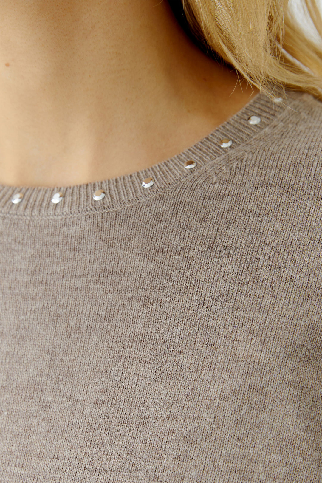 Close-up of a brown sweater with decorative buttons on the neckline.