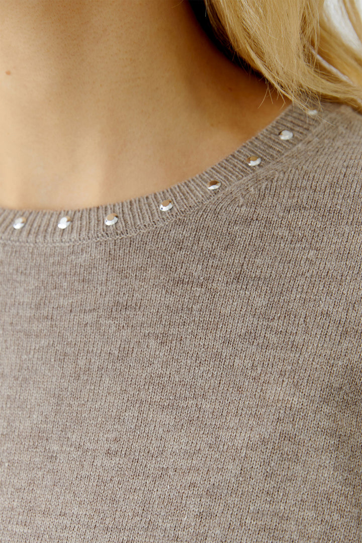 Close-up of a brown sweater with decorative buttons on the neckline.