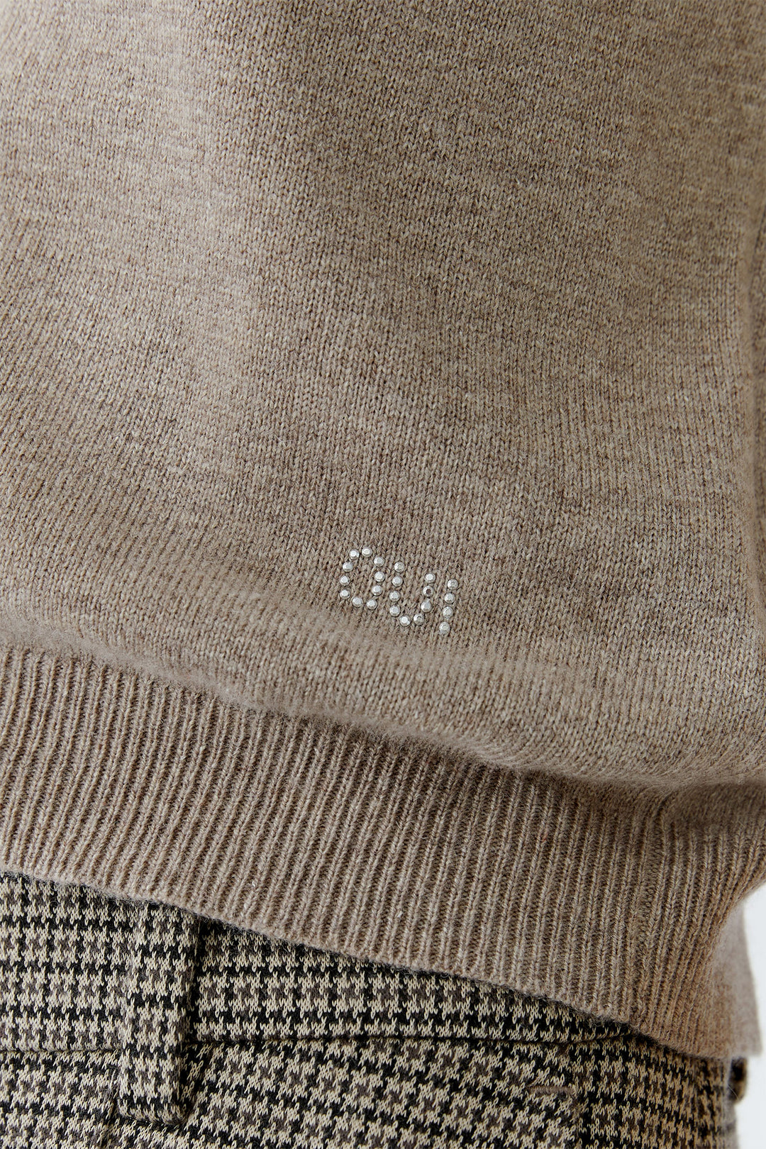 Close-up of a brown sweater with a logo on a blurred background
