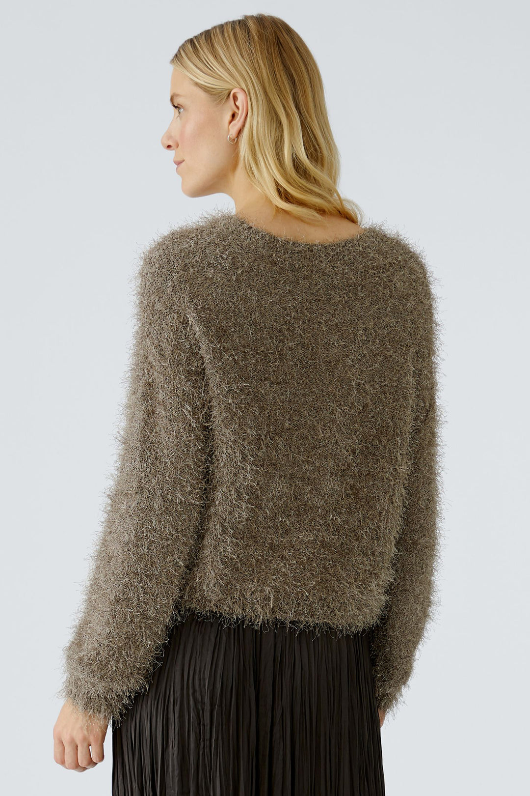 Woman wearing a fluffy brown cardigan against a light gray background