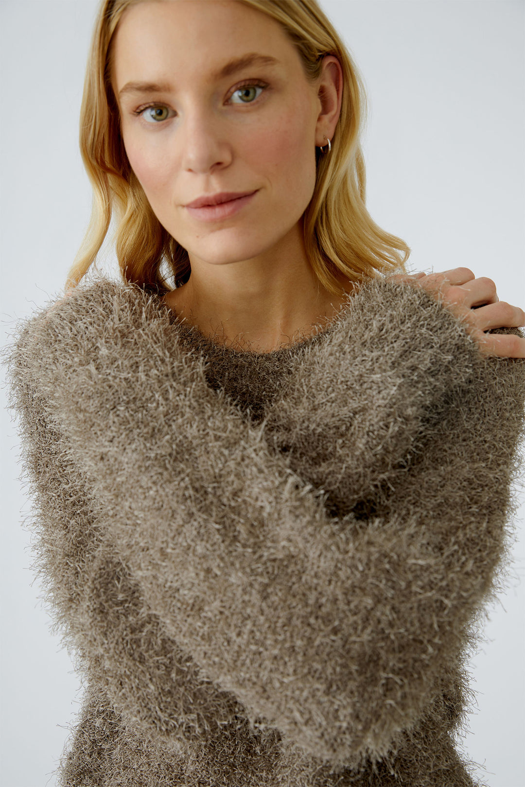 Woman wearing a fluffy brown sweater against a plain background