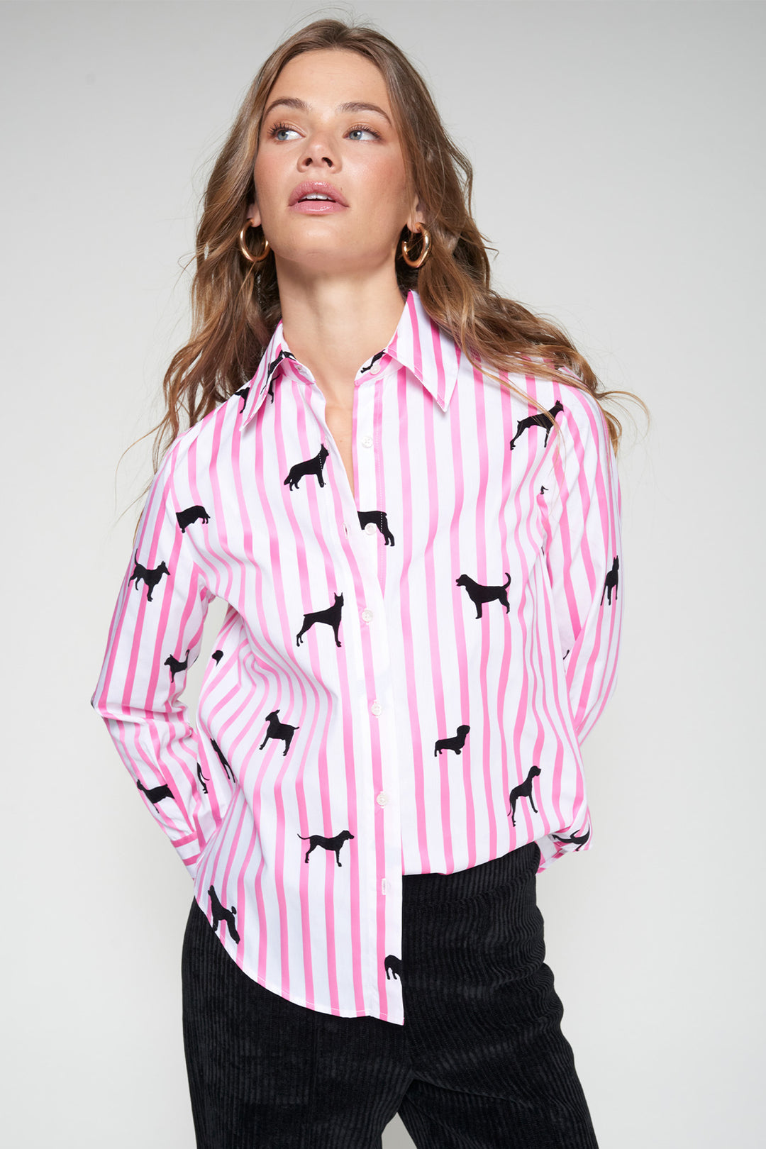 Woman wearing a pink and white striped shirt with black dog patterns on a plain background