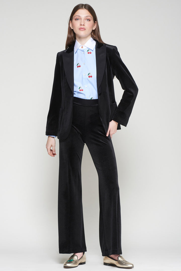 Person wearing a black suit with a light blue shirt featuring red cherry patterns on a white background