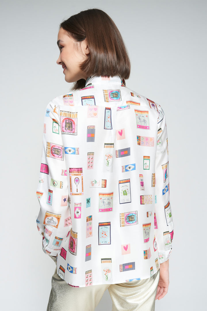 Person wearing a white shirt with colorful graphic design on a plain background