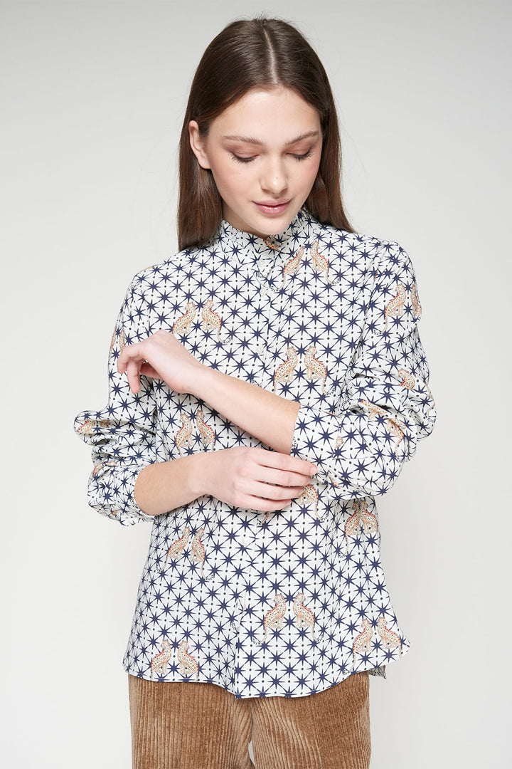 Woman wearing a patterned blouse with long sleeves on a plain background
