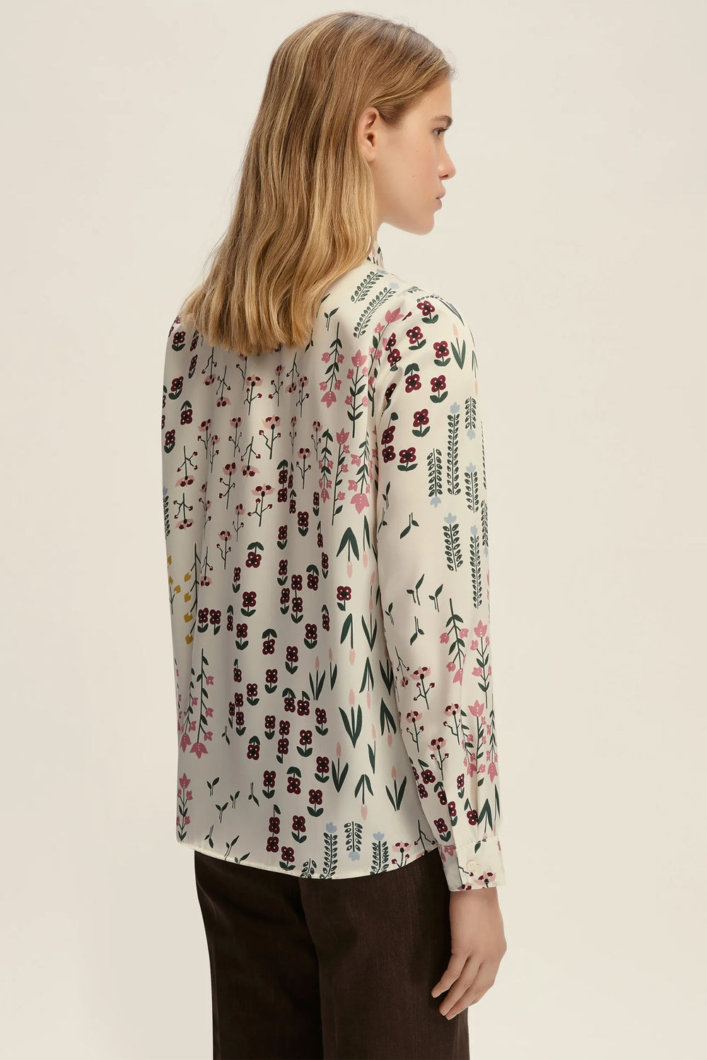 Woman wearing a floral patterned blouse against a plain background