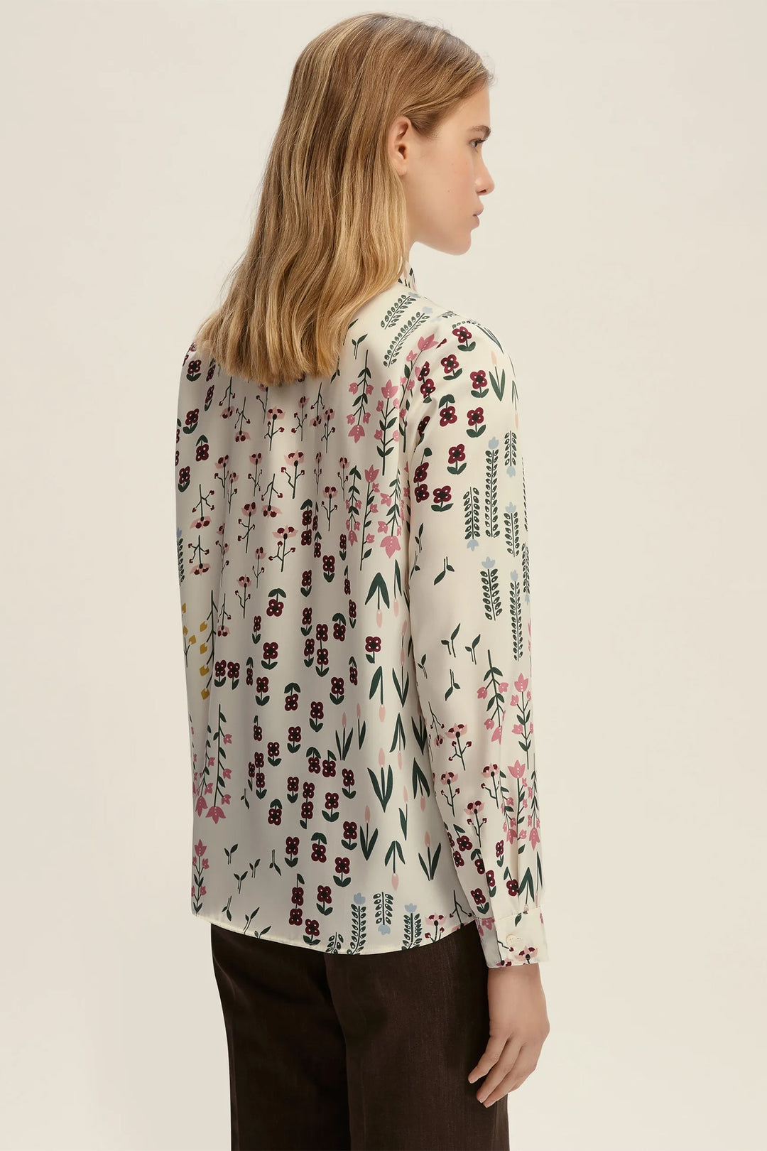 Woman wearing a floral patterned blouse against a plain background